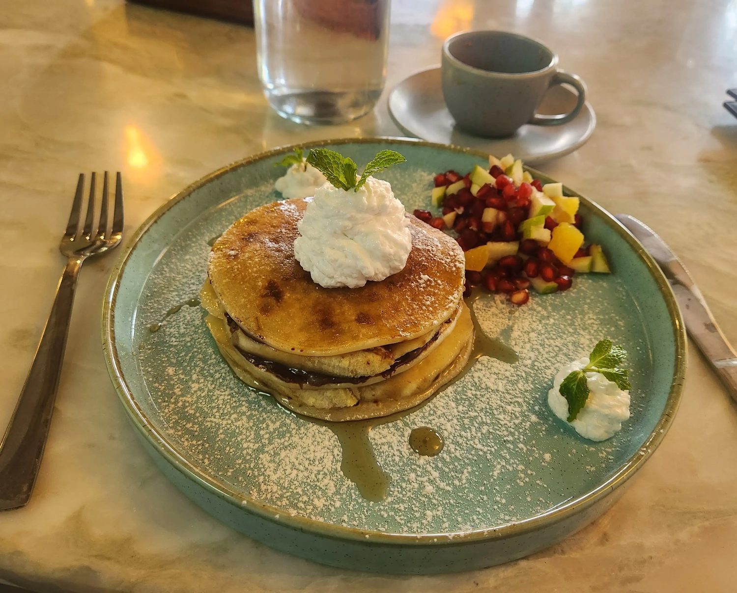 A stack of American pancakes with fresh fruit and cream