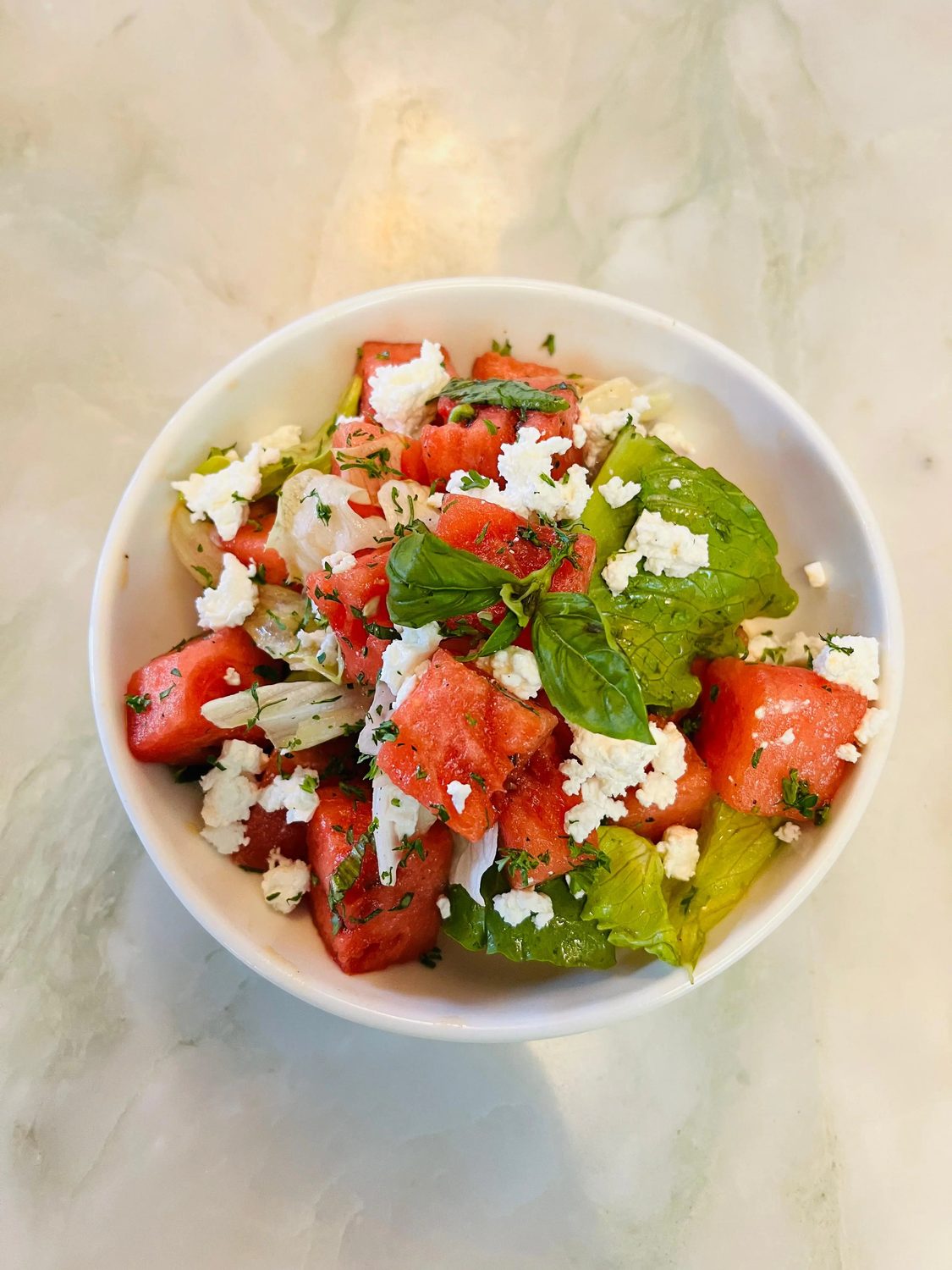Watermelon, basil and feta salad in a white bowl